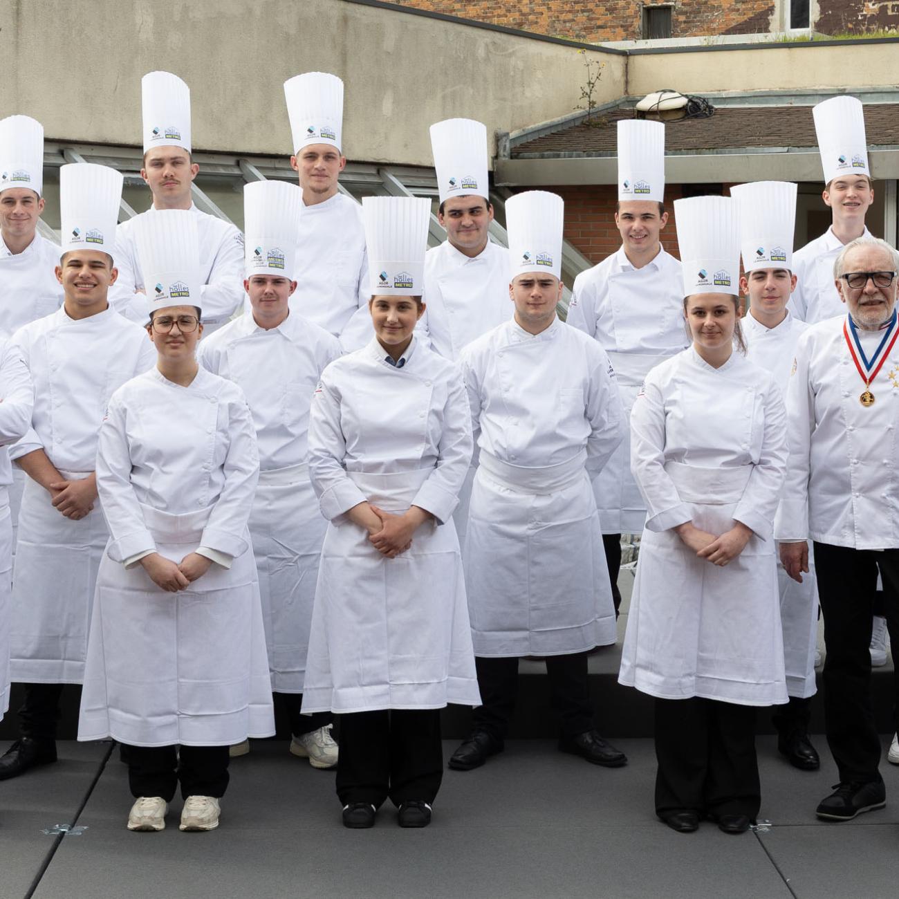 L'ensemble des participants du MAF 2025 et apprentis charcutiers-traiteurs en tablier avec David Bret, MOF charcutier-traiteur et Joël Mauvigney, président de la CNCT